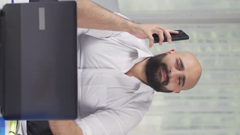 Vertical-video-of-Home-office-worker-man-getting-bad-news-on-the-phone.